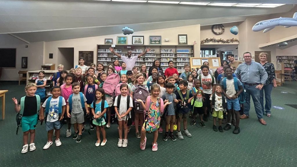 U.S. Sugar’s Brannan Thomas, Ryan Duffy and Vicki Markham with Clewiston students after handing out backpacks and supplies at the Clewiston Library.