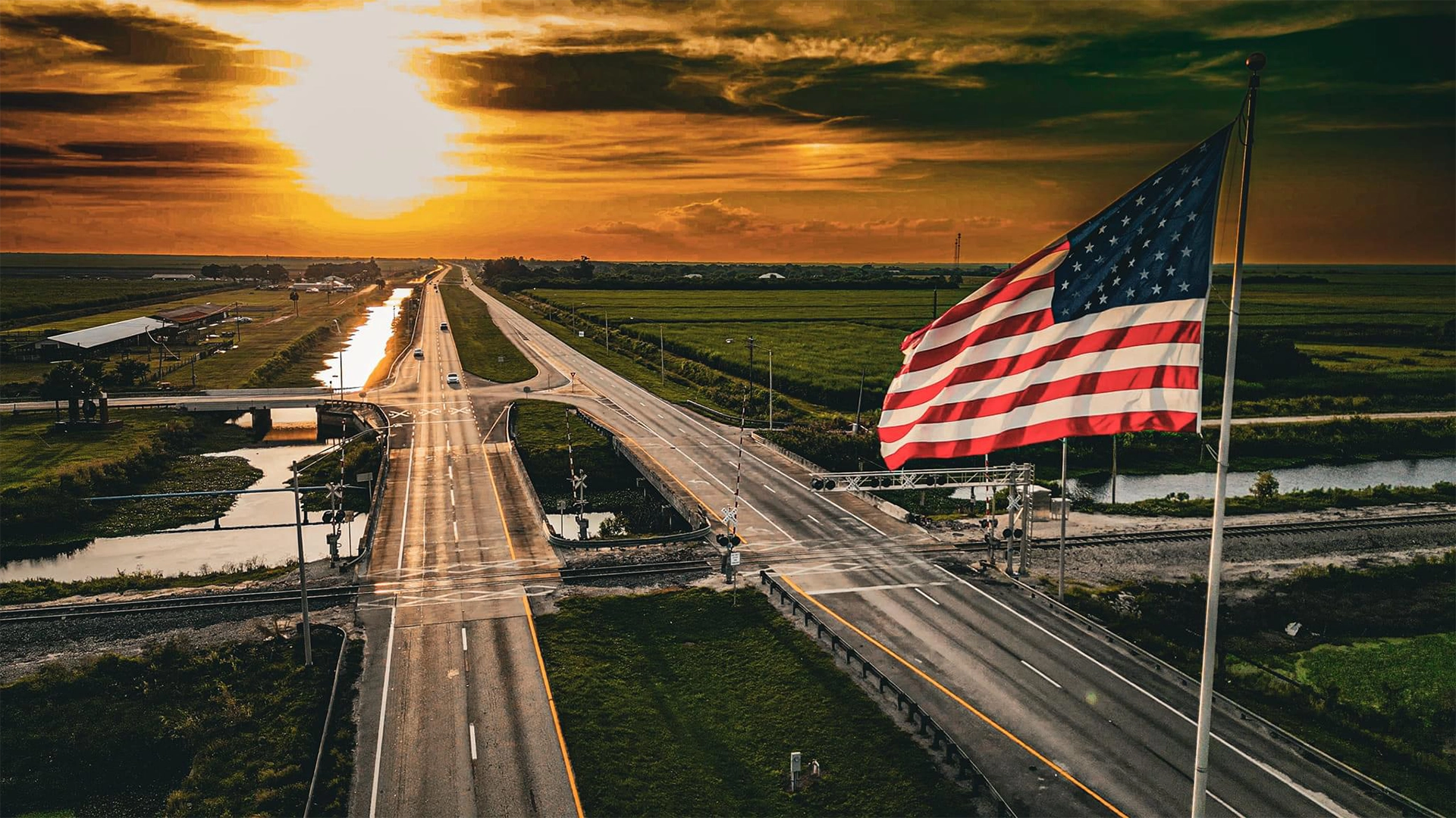 American flag in front of highway at sunset