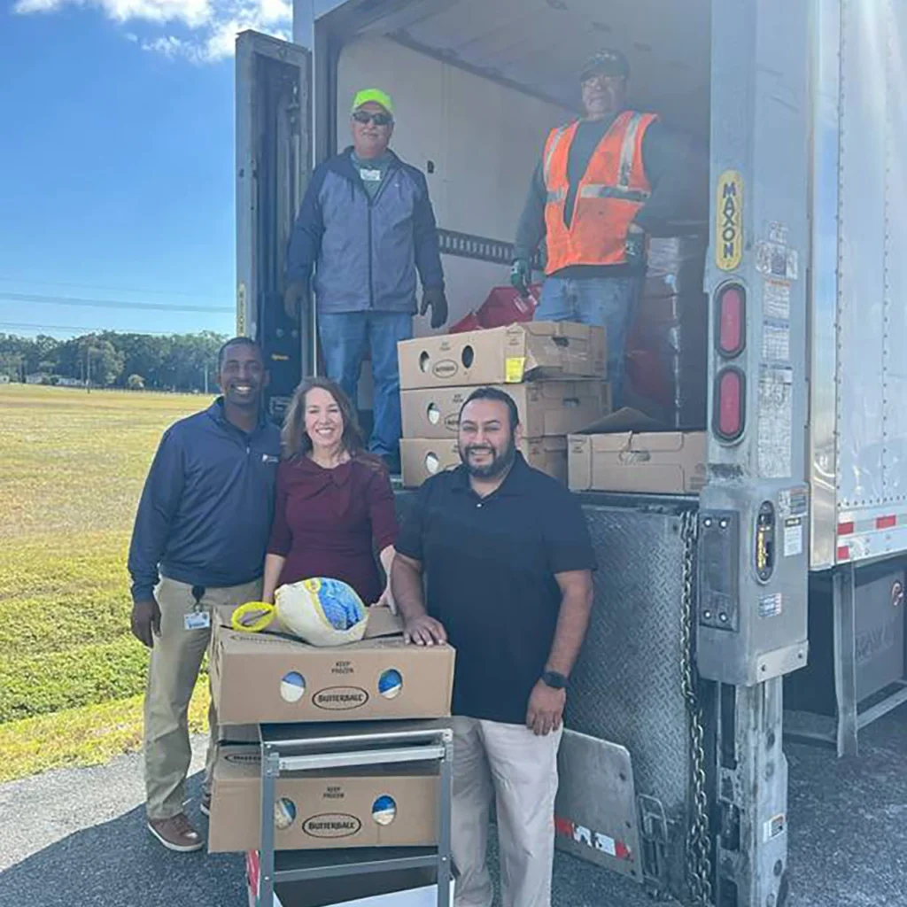 U.S. Sugar’s Abelardo Gonzalez and Felipe Ramirez (on truck) and Brannan Thomas, Hendry County Tax Collector Amy Collins, and Customer Service Office Manager Luis Perez at a turkey delivery stop in Clewiston.
