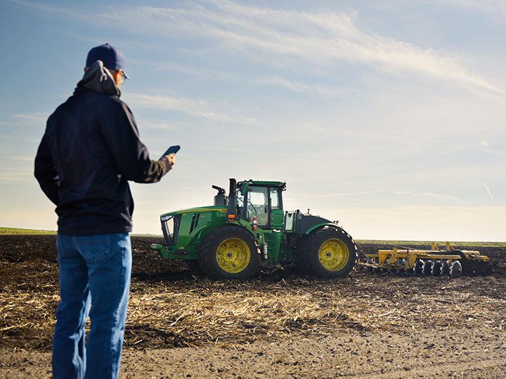 A farm worker monitors equipment in a sugarcane field using technology that supports modern American farming.