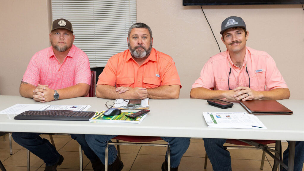 Three U.S. Sugar employees wearing pink shirts gather around a conference table in support of Breast Cancer Awareness Month.